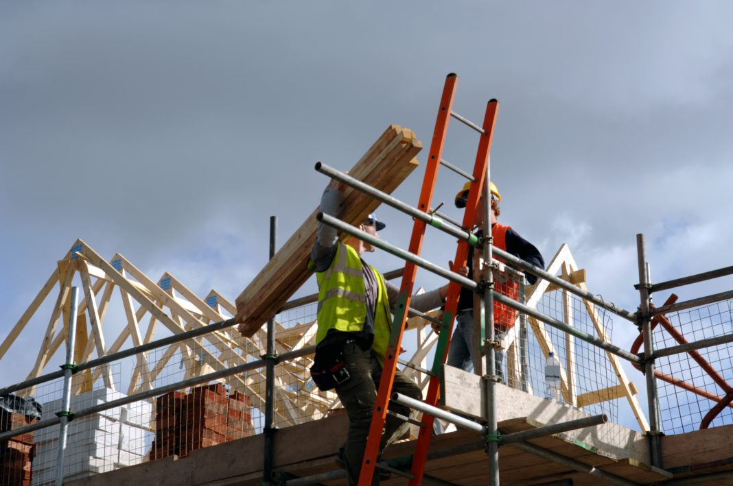 A pair of roofers working on a construction site in Manchester, England, representing Assent's acquisition of Clarke Banks Group