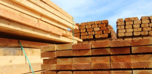 Photo showing some huge piles of wooden planks and fence posts, freshly sawn up in a sawmill and piled in the timber yard, ready to be sold to the general public.