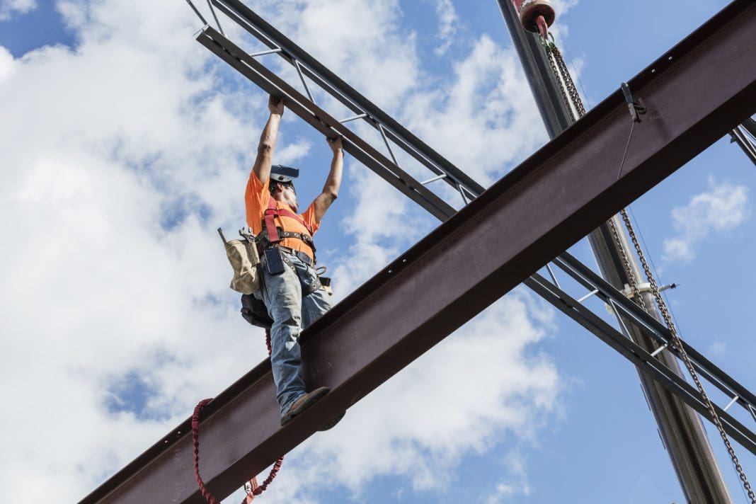 A worker erecting a steel frame construction, the kind Intrastack encourages offsite construction of