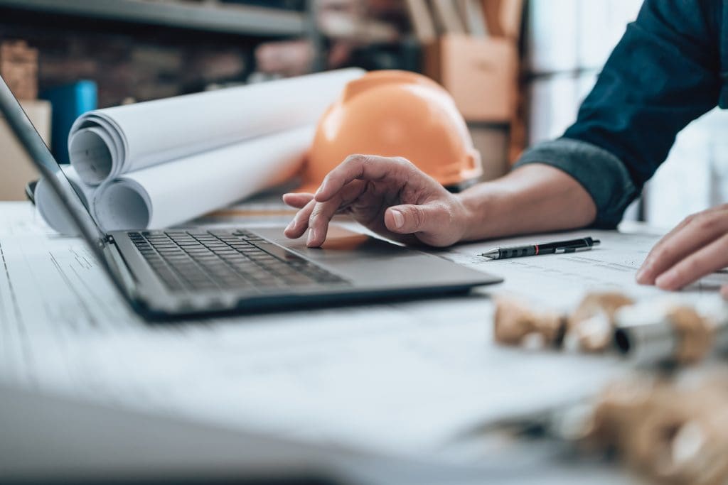 Engineering working with drawings inspection on laptop in the office and Calculator, triangle ruler, safety glasses, compass, vernier caliper on Blueprint. Engineer, Architect, Industry and factory concept, representing document control