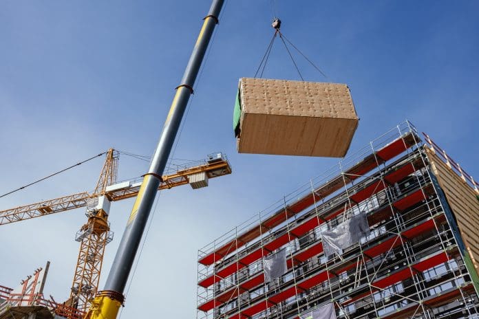 Construction site of a building with a crane lifting a modular section into place representing MMC in Ireland