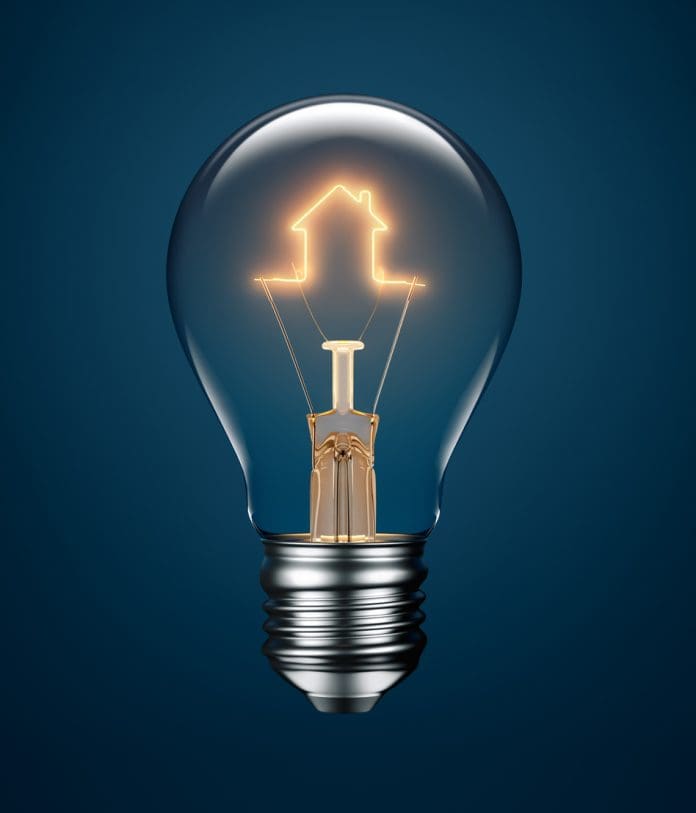 A close up of a lightbulb with a filament in the shape of a house representing Construct Innovate's research into housing