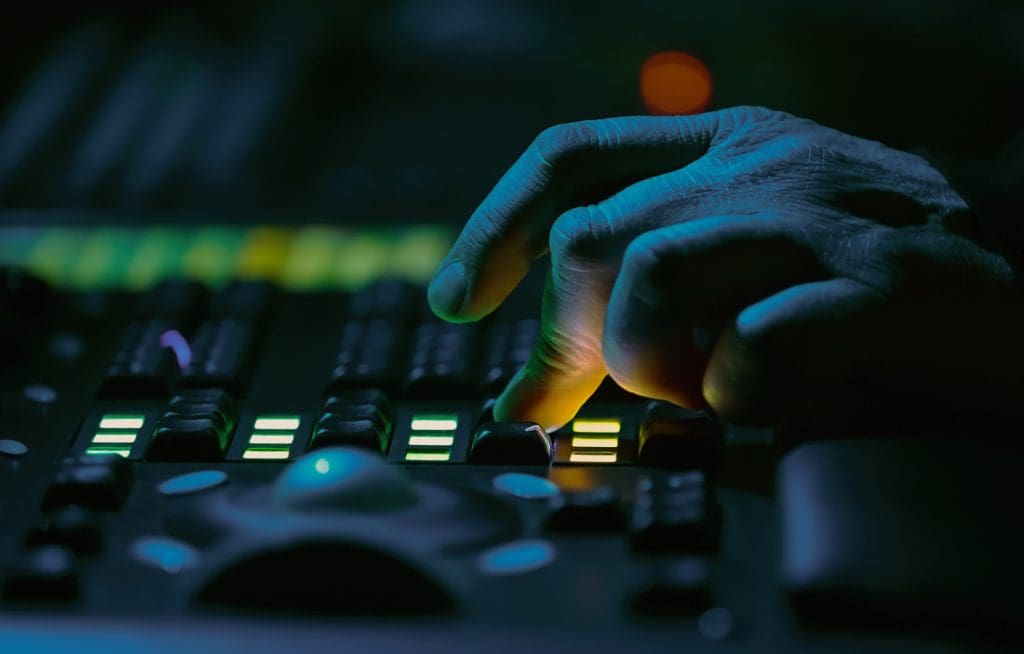 Sound technician works on audio mixer panel at rock concert in nightclub.Professional working on mixing controller at festival in music hall.Hand of specialist adjusting volume on party in the club