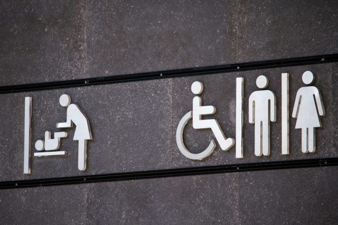 All genders and disabled toilet sign, changing room sign, minimal sign design on gray wall, selective focus