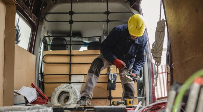 Electrician wearing protective gloves and helmet is preparing cables and equipment inside his van, getting ready for an installation job, representing the need for EPLI