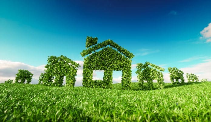 Sustainable eco village concept. 3d rendering of house symbols on fresh spring meadow with blue sky in background