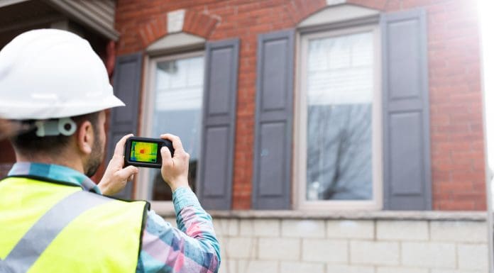 Home inspector using thermal camera to analyse the heat loss of a house