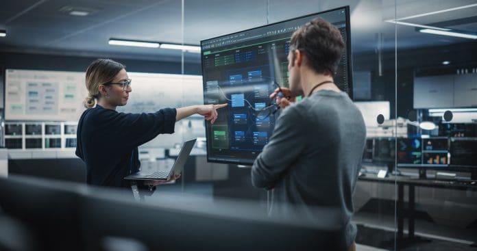 Two Diverse Software Developers Having a Meeting in a Conference Room. Female and Male Tech Industry Engineers Brainstorming Ideas for Their Neural Network Blockchain Startup, representing AI in construction