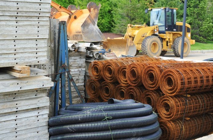 Various piles of building materials (concrete, tubing, wire) at a construction site.